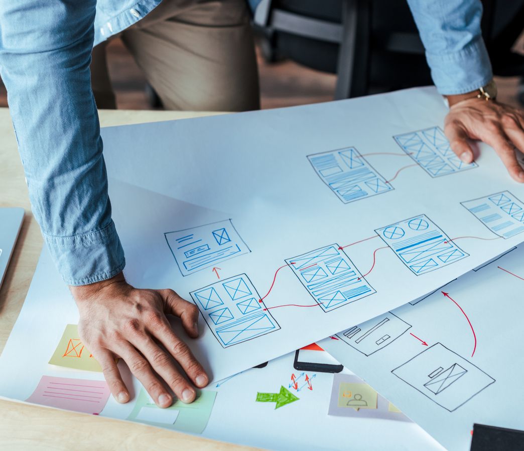 a person leaning over a printed wireframe on a table